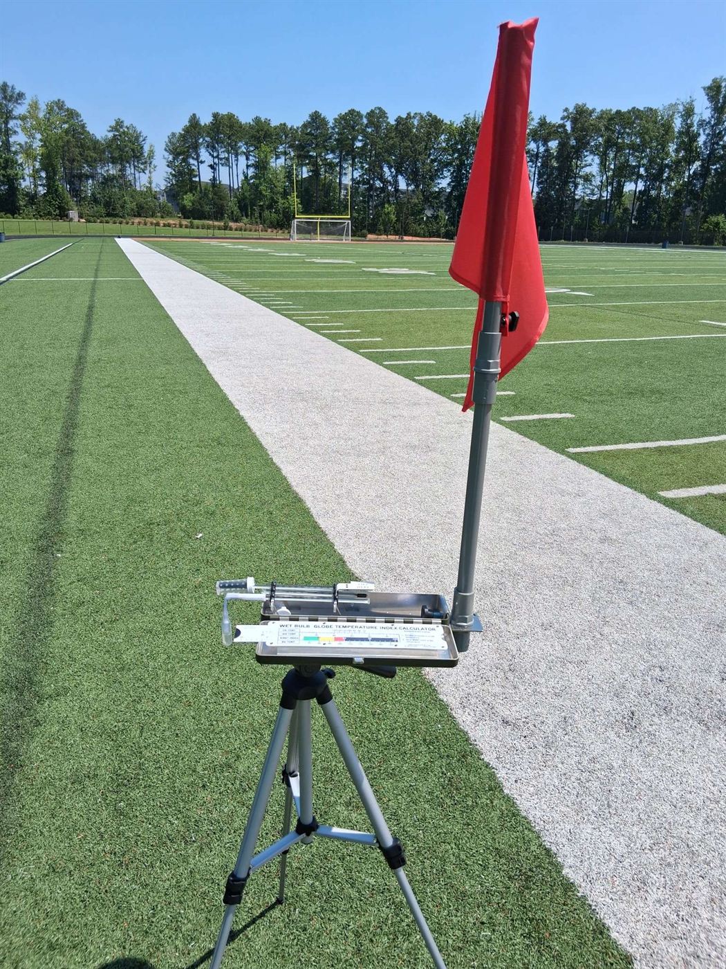 Premium WBGT Kit with red heat-category flag deployed on the sideline of an athletic field